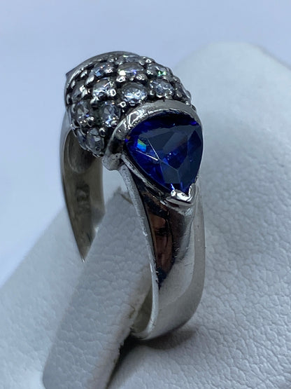 Anillo solitario en mano, luciendo la circonia azul con máximo brillo