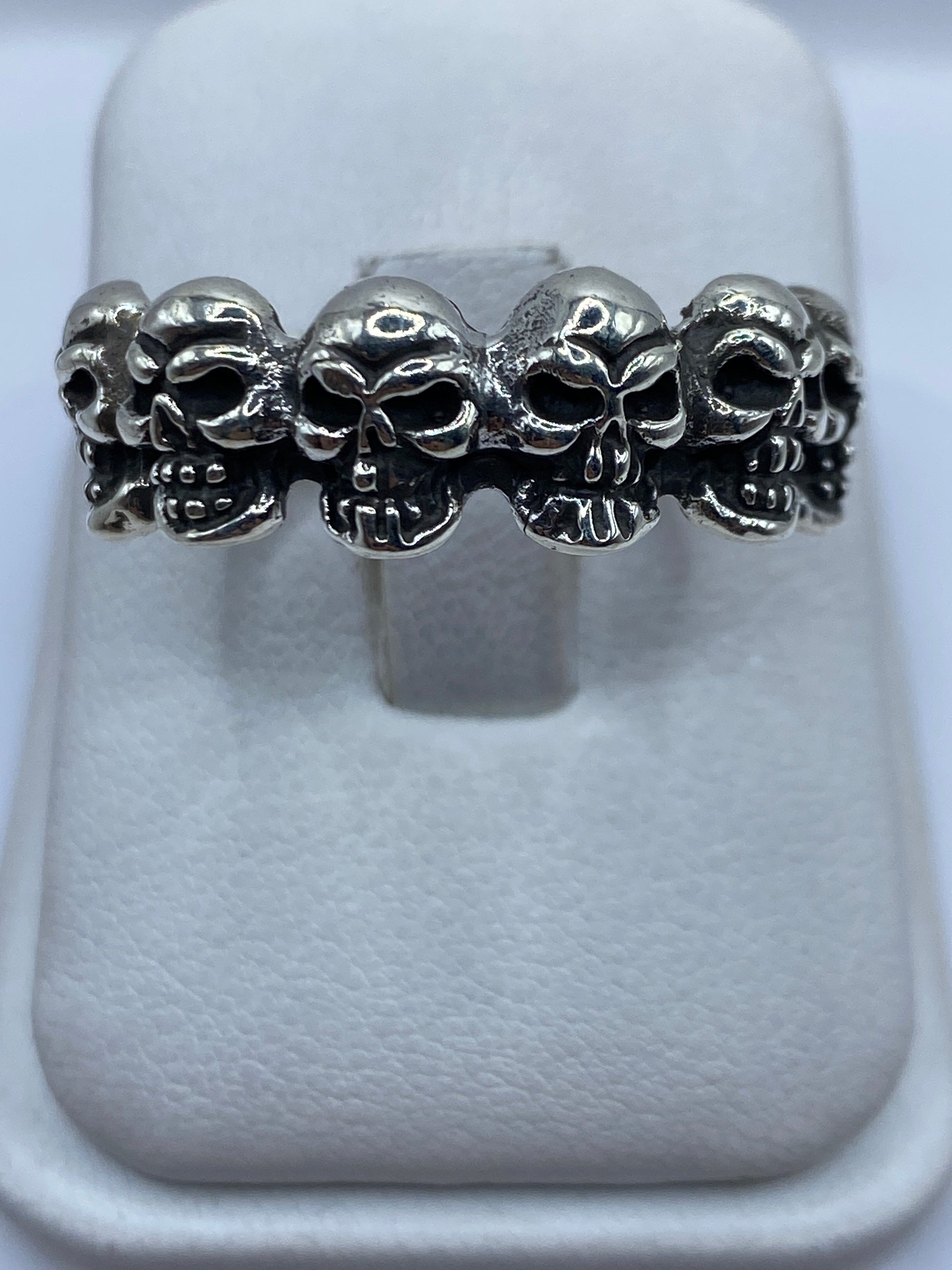 Anillo de cinco calaveras en plata .925 visto desde arriba sobre banda blanca
