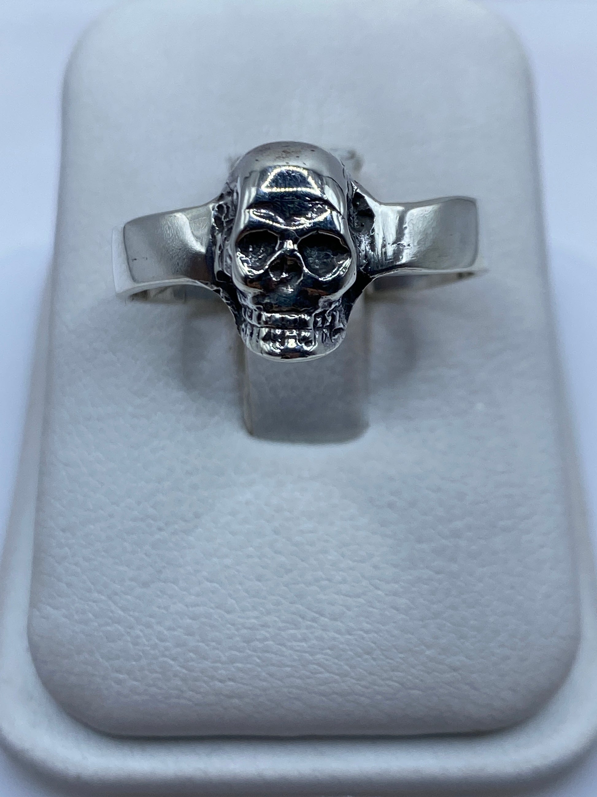 Anillo calavera de plata .925 pulida sobre anillo display de tela blanca, vista frontal