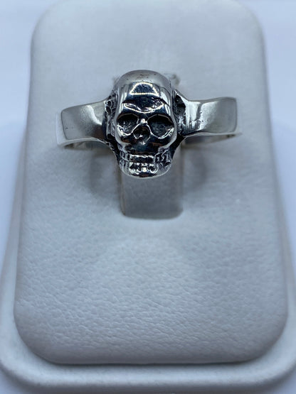 Anillo calavera de plata .925 pulida sobre anillo display de tela blanca, vista frontal