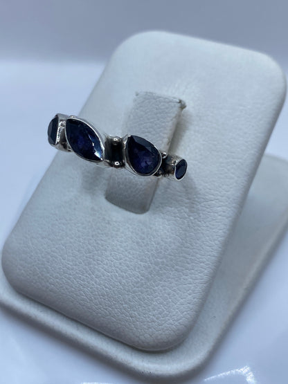 Vista frontal del anillo solitario circonia azul en la mano de una mujer