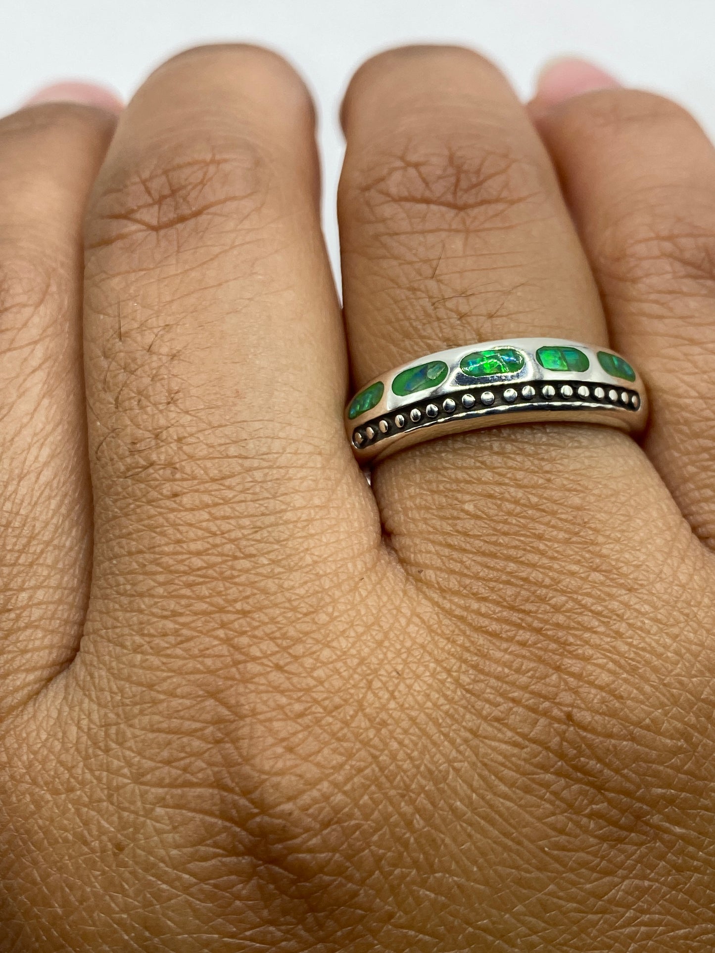 Anillo con ópalo de fuego puesto en dedo, mostrando el brillo y fuego de la piedra