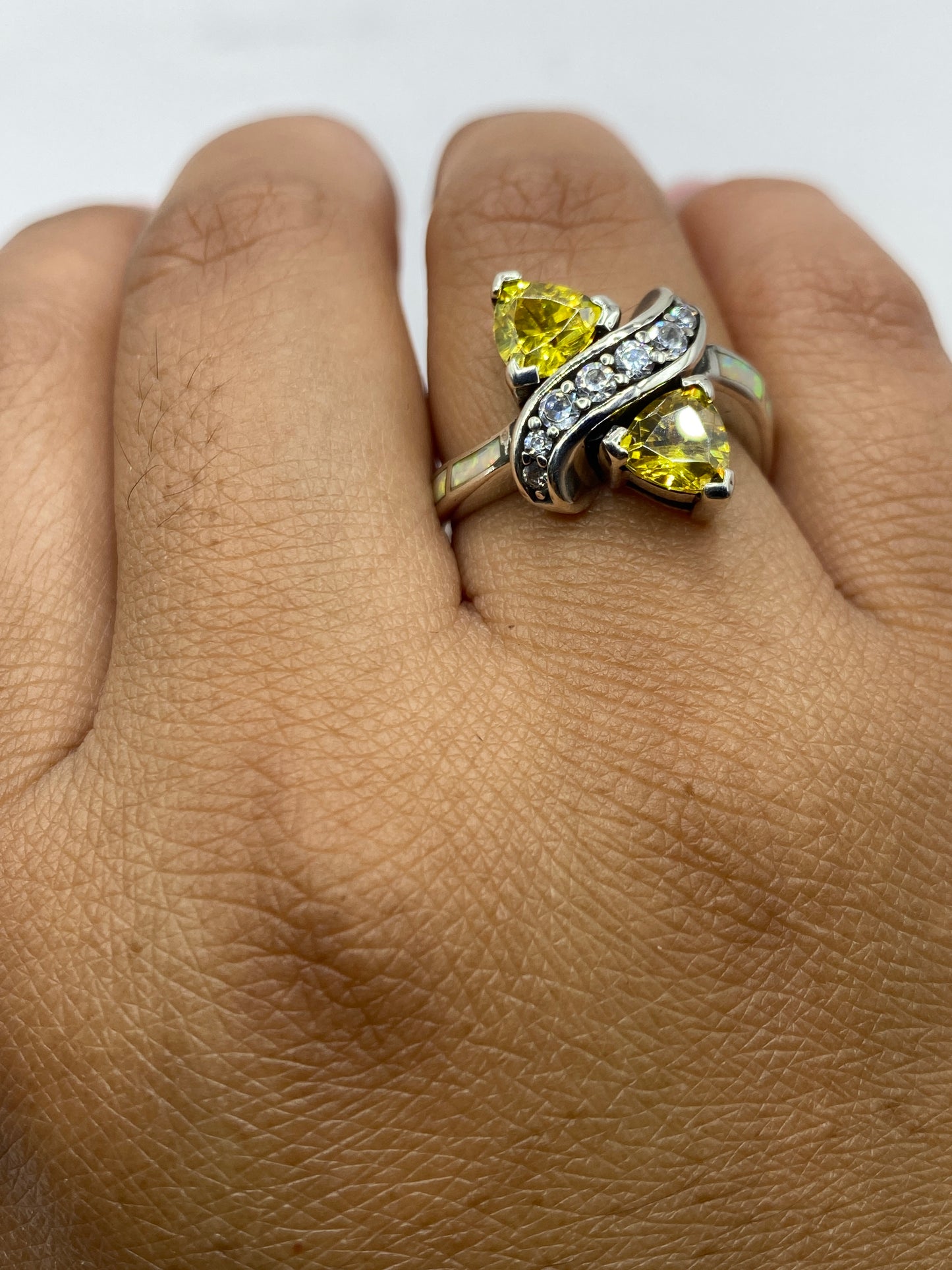 Anillo sobre fondo gris con sello .925 visible, ópalos brillando con colores únicos