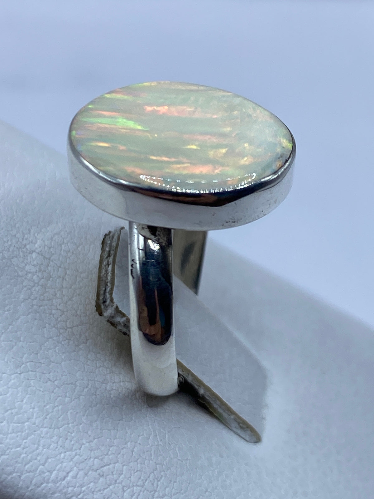 Detalle del ópalo de fuego natural con reflejos rojo, verde y amarillo en el centro del anillo