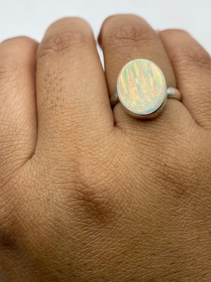 Anillo ajustable de ópalo de fuego en mano de mujer mostrando el juego de colores único