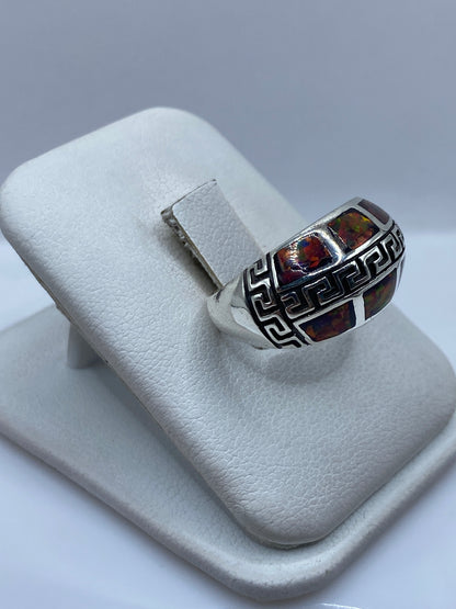 Anillo étnico en plata pura con ópalo fuego natural mostrando tonos rojo naranja y verde, en dedo