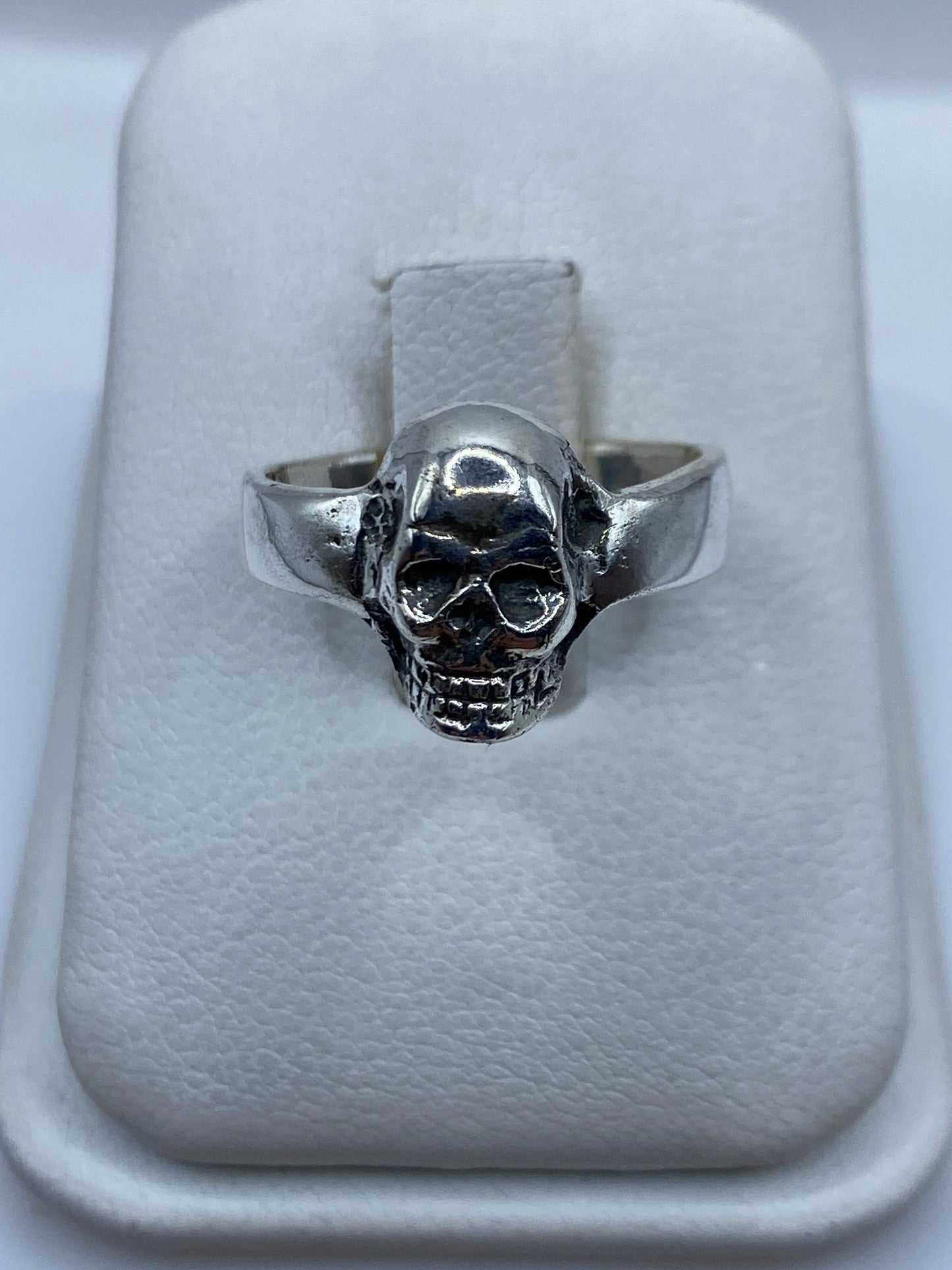 Anillo de plata calavera pulida sobre almohada blanca, talla 7