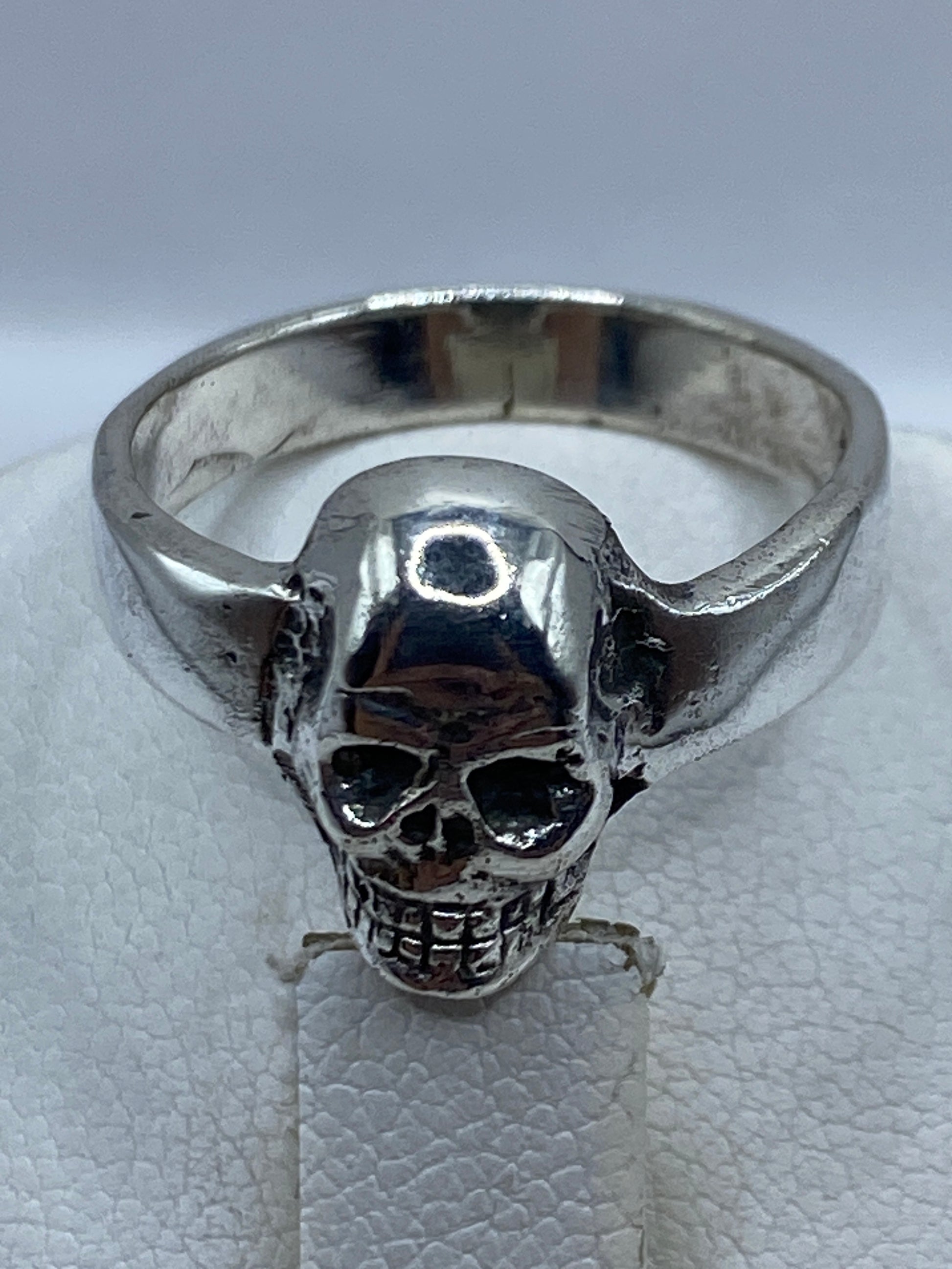 Anillo calavera de plata en mano de hombre adulto, uso diario