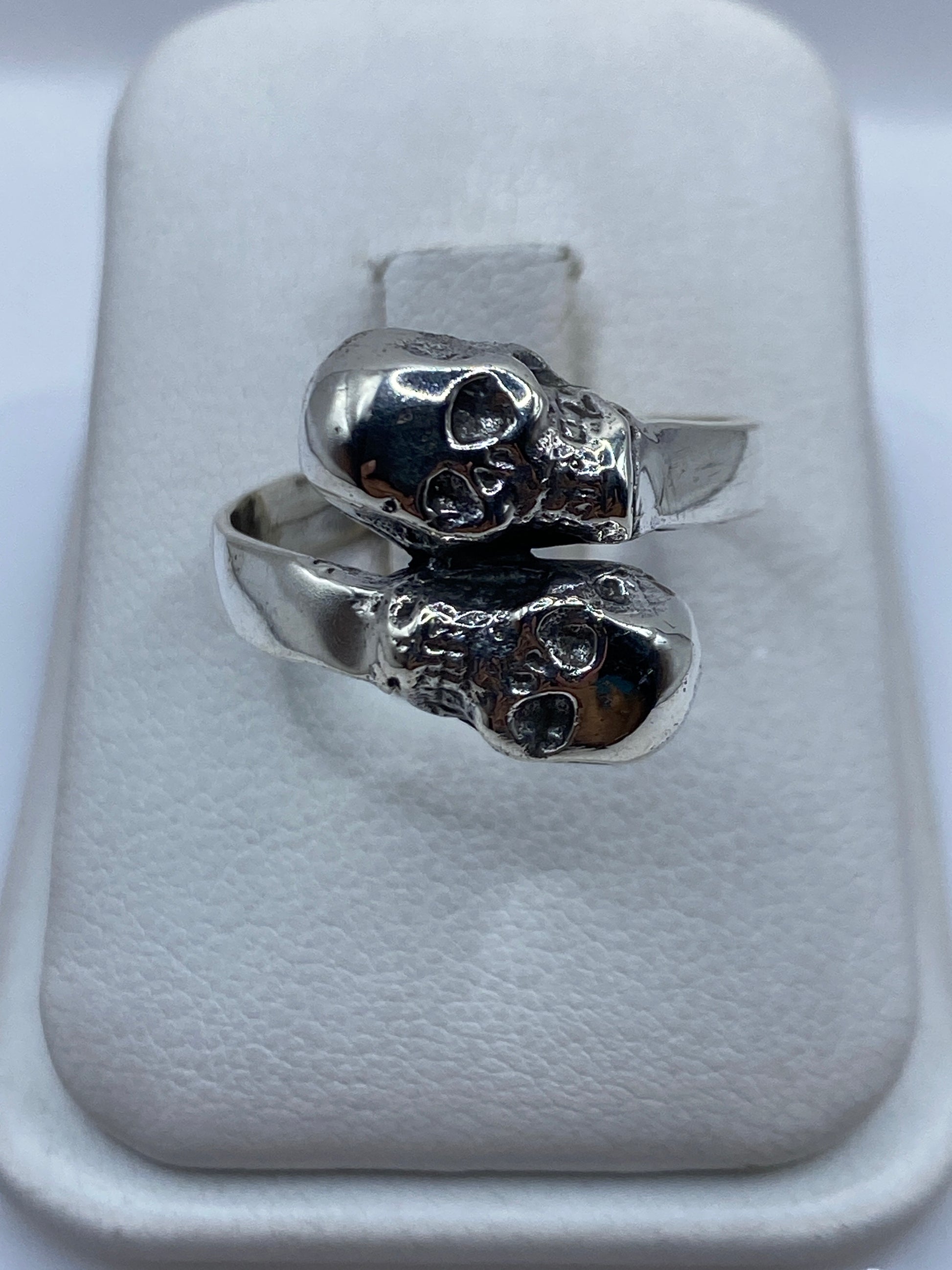Anillo de plata con calaveras dobles talladas, diseño étnico de Taxco en mano de hombre