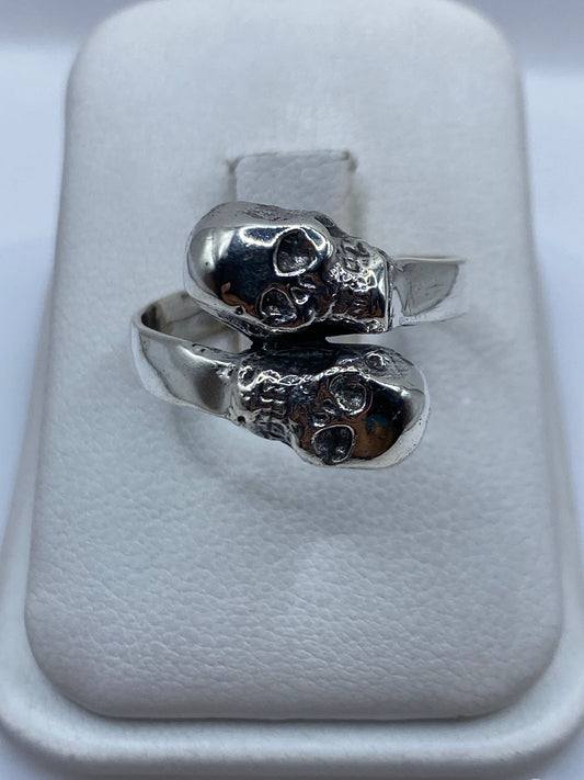 Anillo de plata con calaveras dobles talladas, diseño étnico de Taxco en mano de hombre