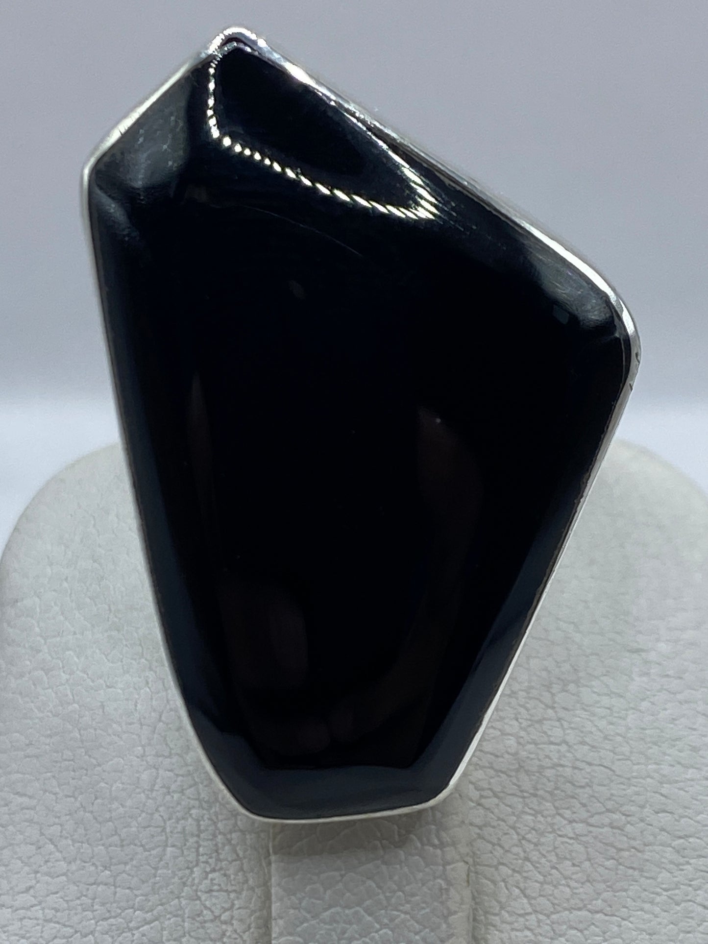 Anillo ajustable de ónix negro en la mano, detalle del pulido espejo