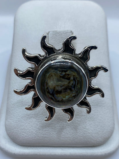 Anillo sol de plata .925 con piedra natural marrón oscura, vista frontal sobre base blanca