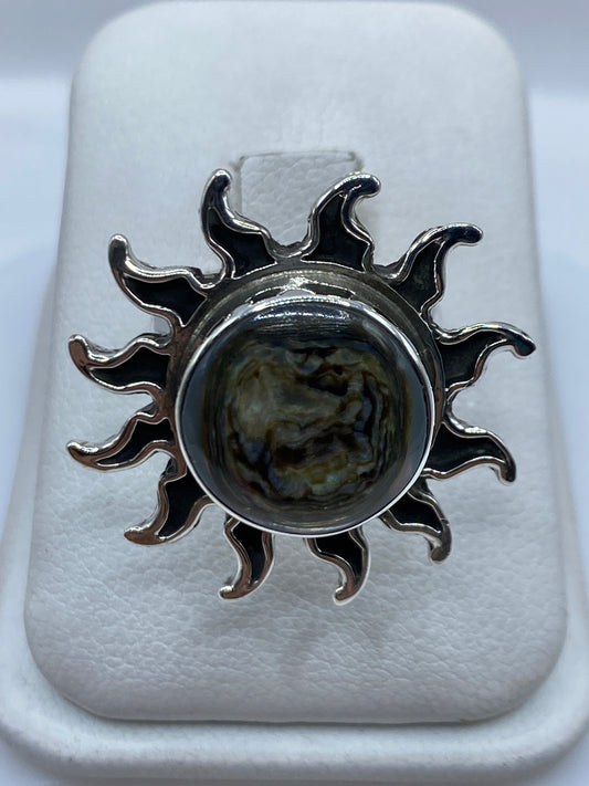 Anillo sol de plata .925 con piedra natural marrón oscura, vista frontal sobre base blanca
