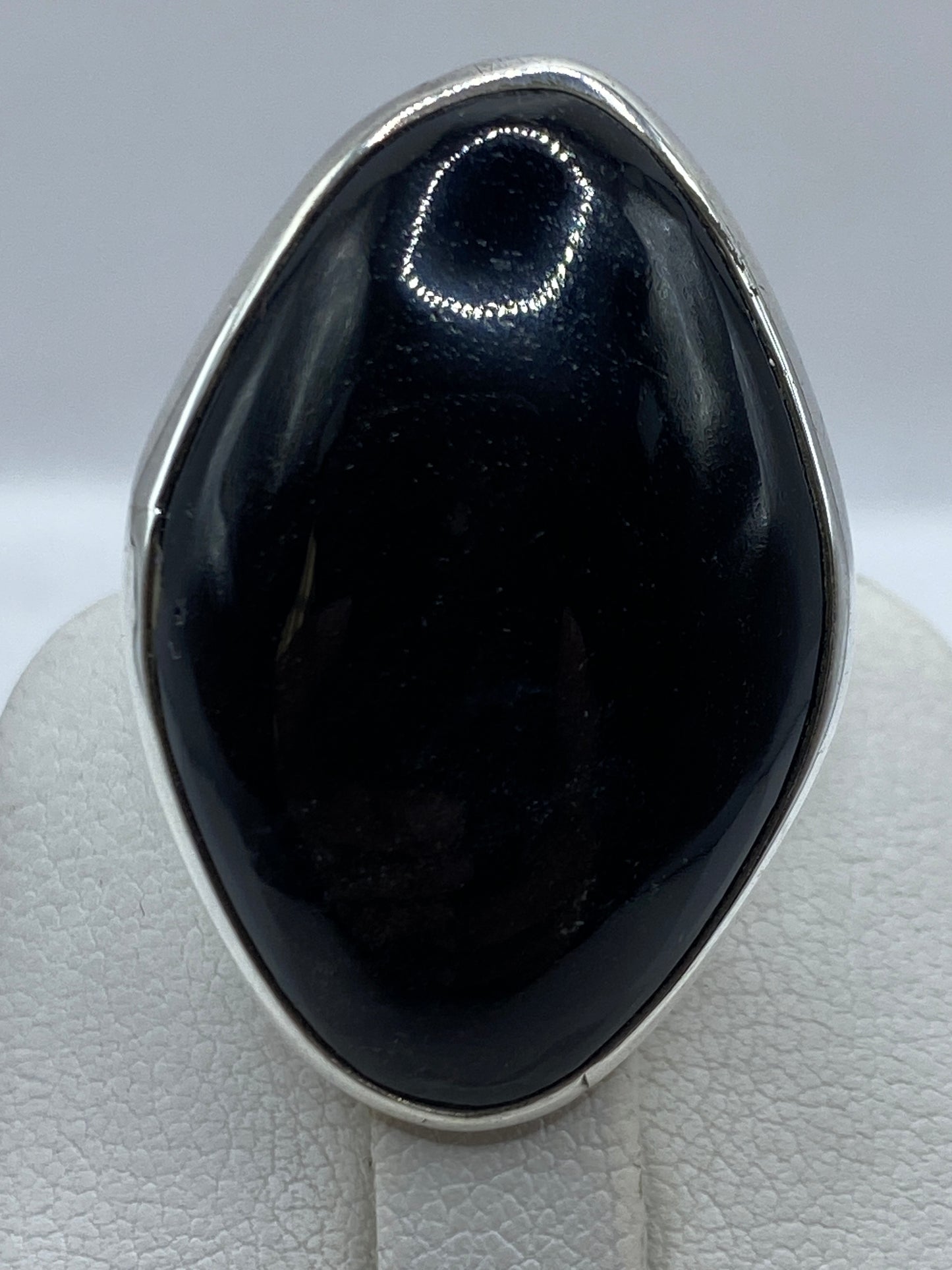 Anillo solitario de onix en la mano, mostrando el brillo profundo de la piedra