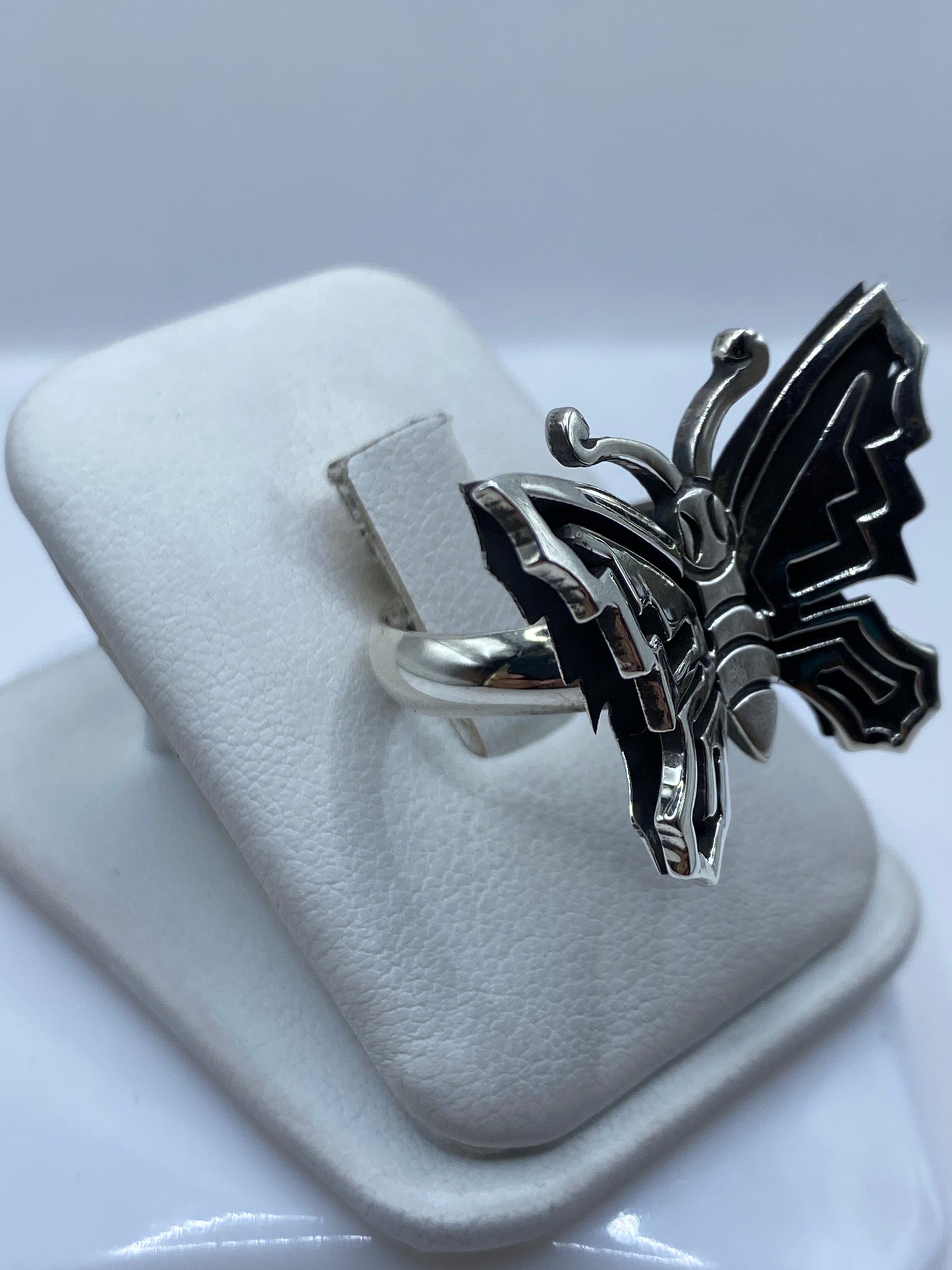 Anillo mariposa ajustable en plata pura en la mano de una mujer, con líneas geométricas marcadas