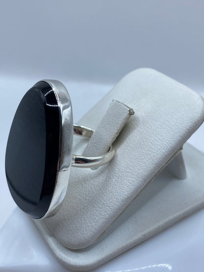 Anillo solitario ónix sobre mano femenina, mostrando el reflejo espejo del ónix negro