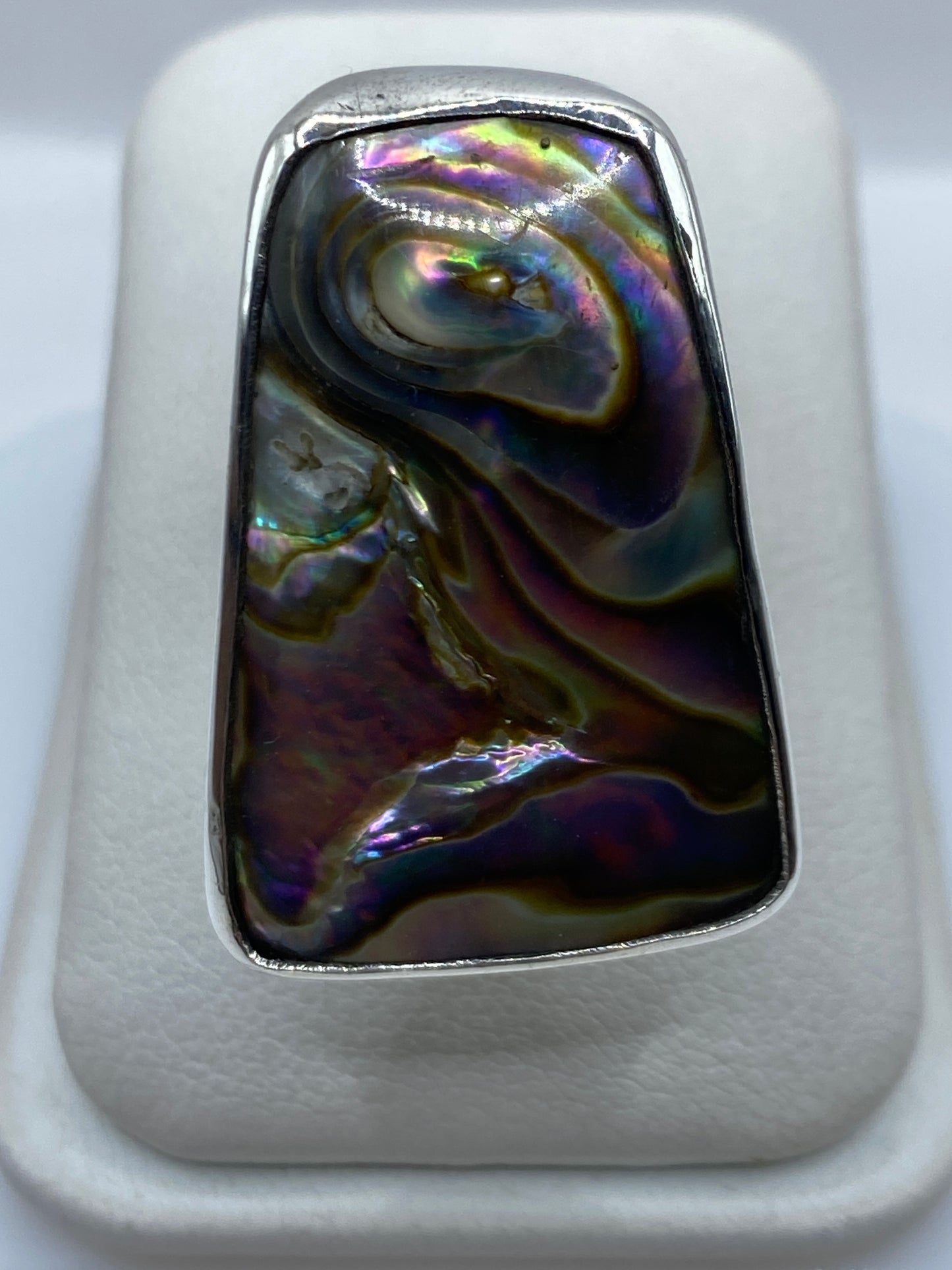 Anillo ajustable de plata con piedra iridiscente multicolor mostrando reflejos púrpura, azul y dorado