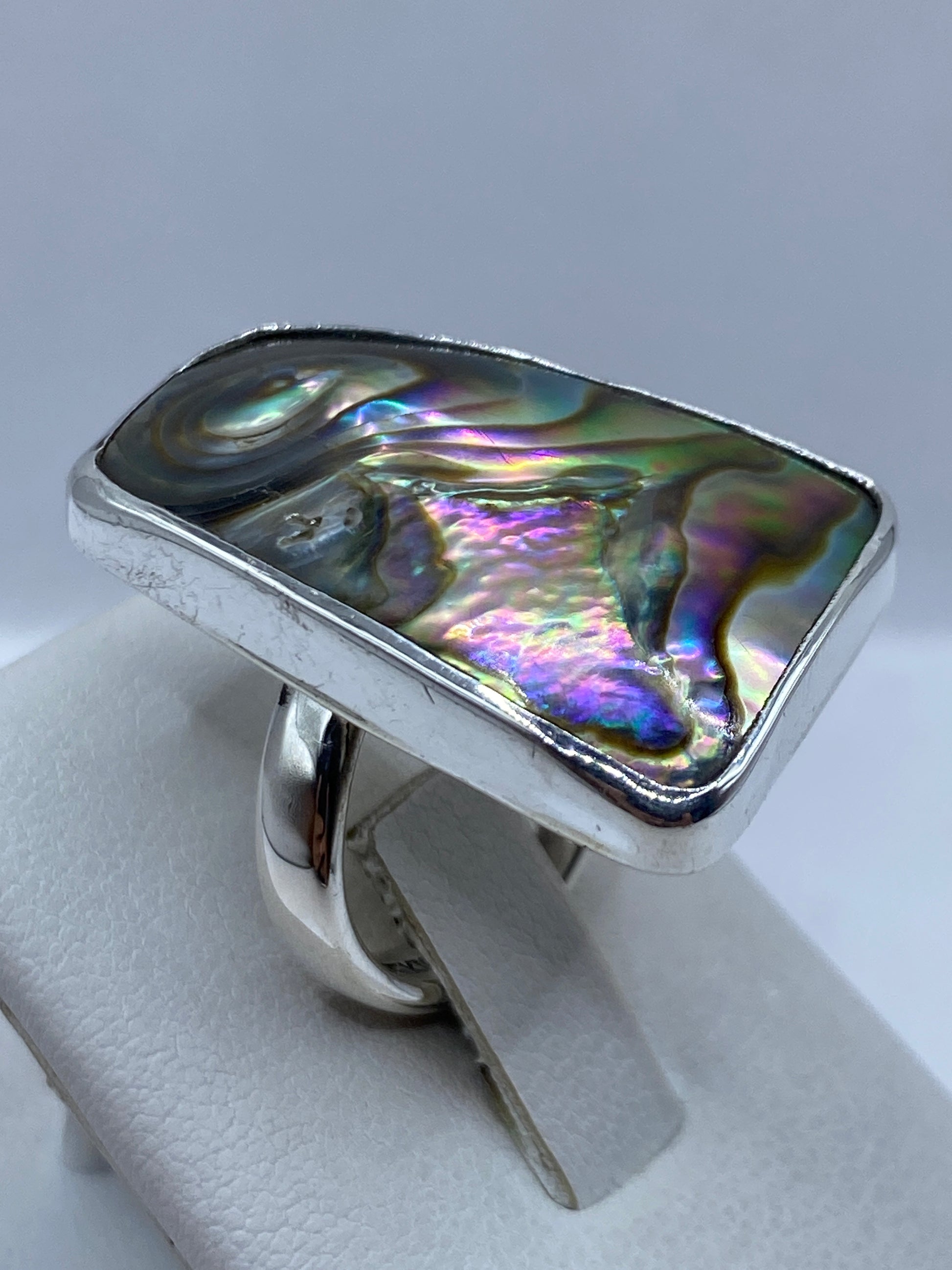 Detalle de la piedra iridiscente con arcoíris de colores reflejados en la mano