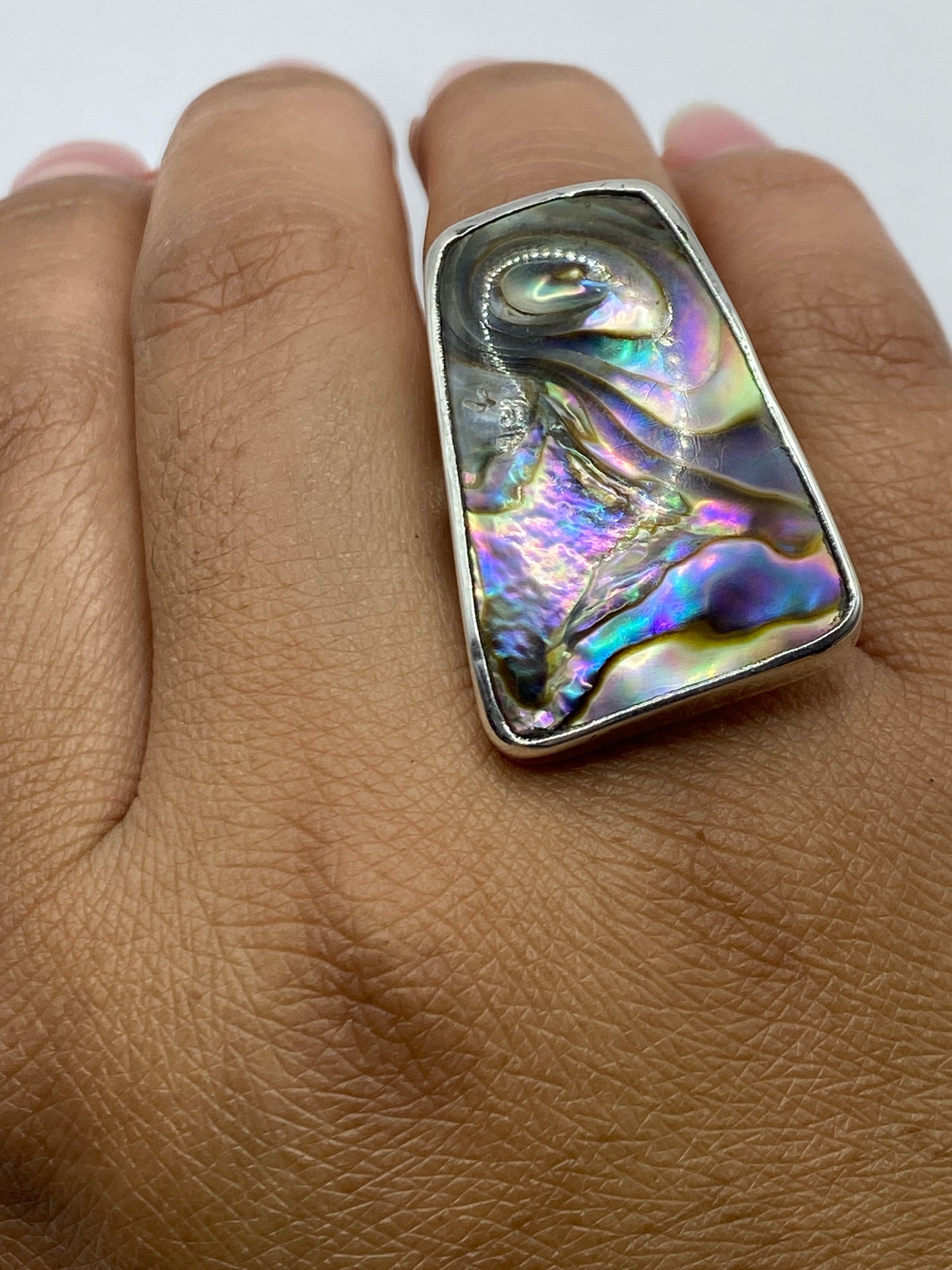 Anillo sobre fondo blanco mostrando el sello 925 y la iridiscencia completa de la gema