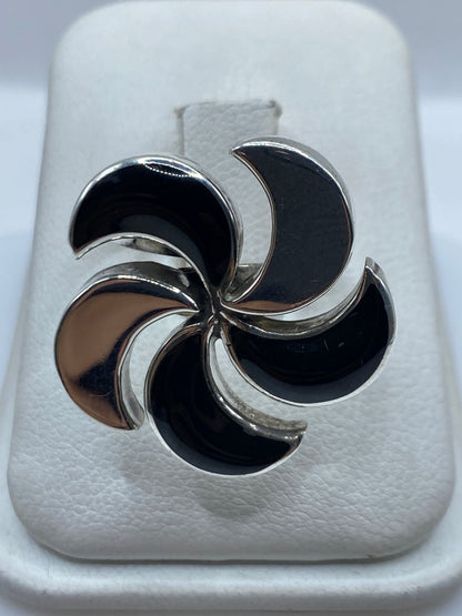 Anillo de plata con ónix negro pulido, ajustable, visto de frente en display blanco