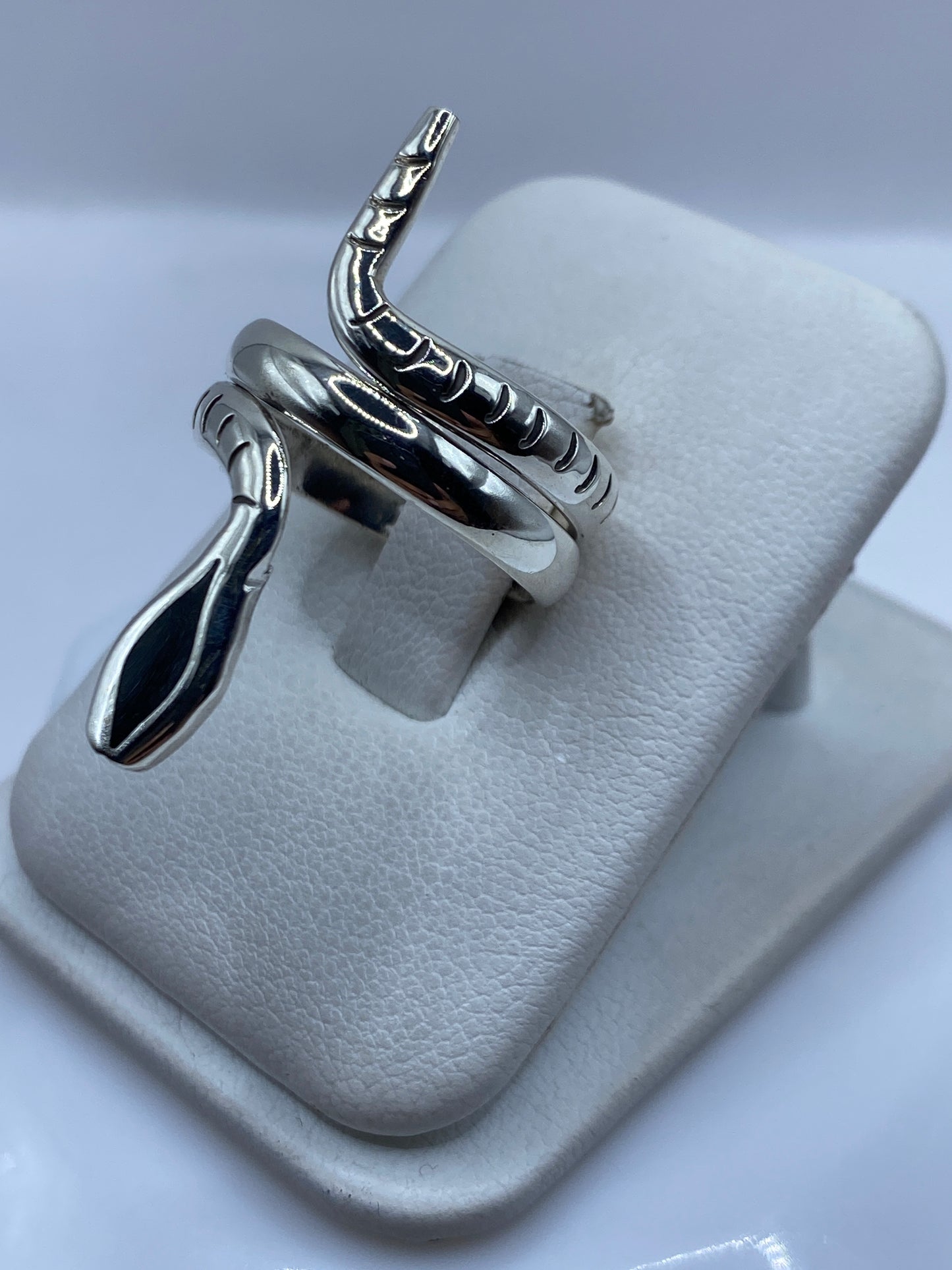 Detalle del anillo escultural de plata en forma de serpiente enroscada