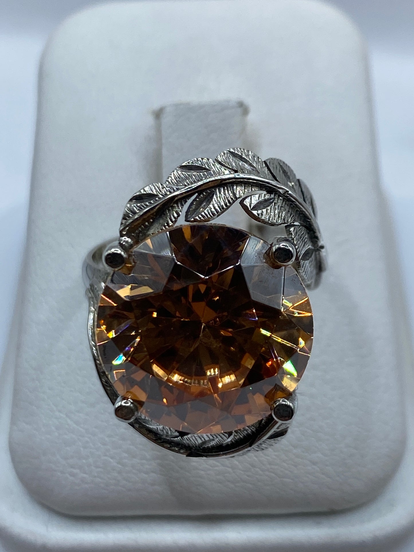 Anillo de plata solitario con circonia champagne y motivo de hojas en relieve textural visto de frente