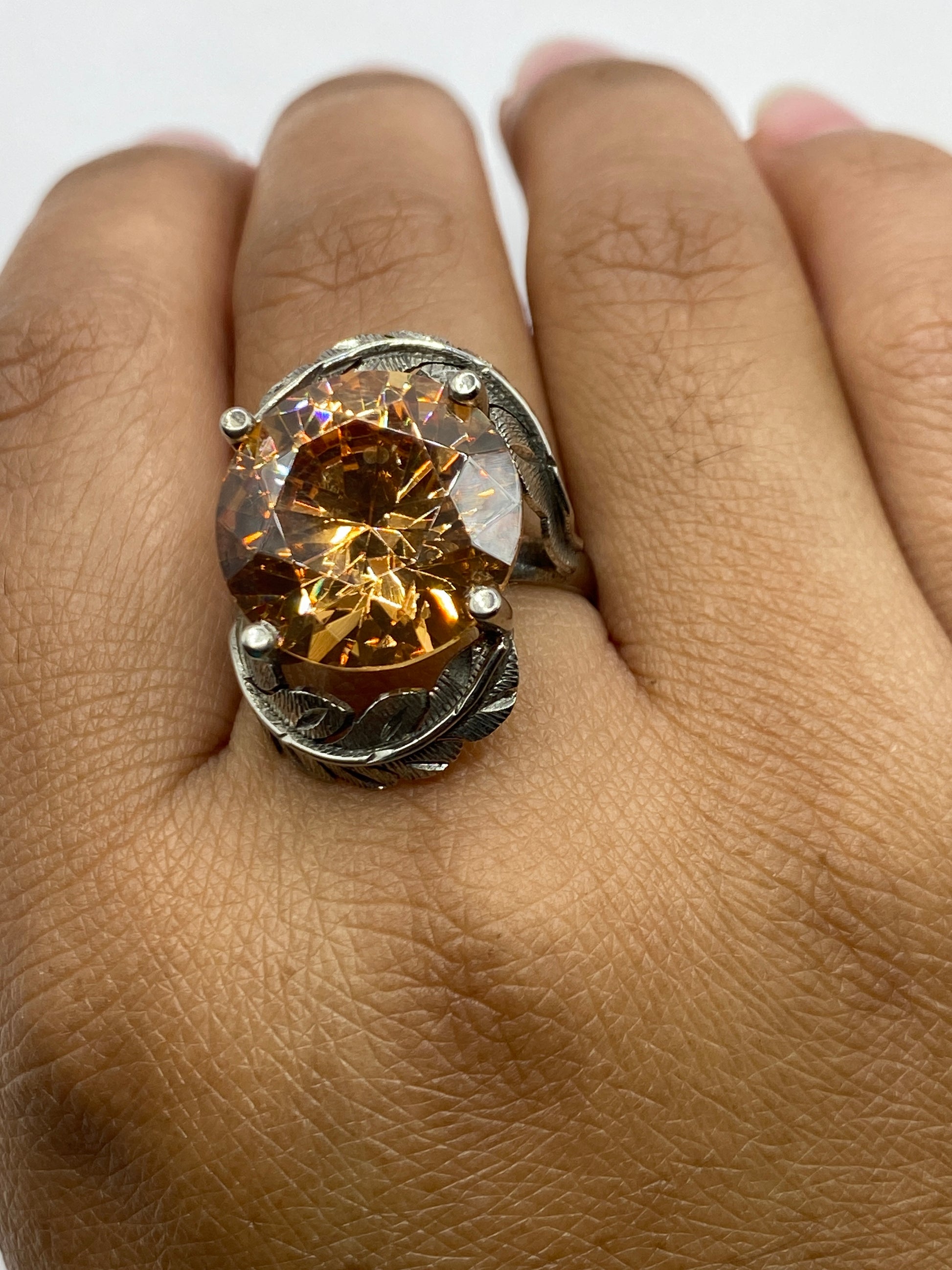 Anillo sobre dedo mostrando brillo cálido de la circonia champagne y textura de relieve