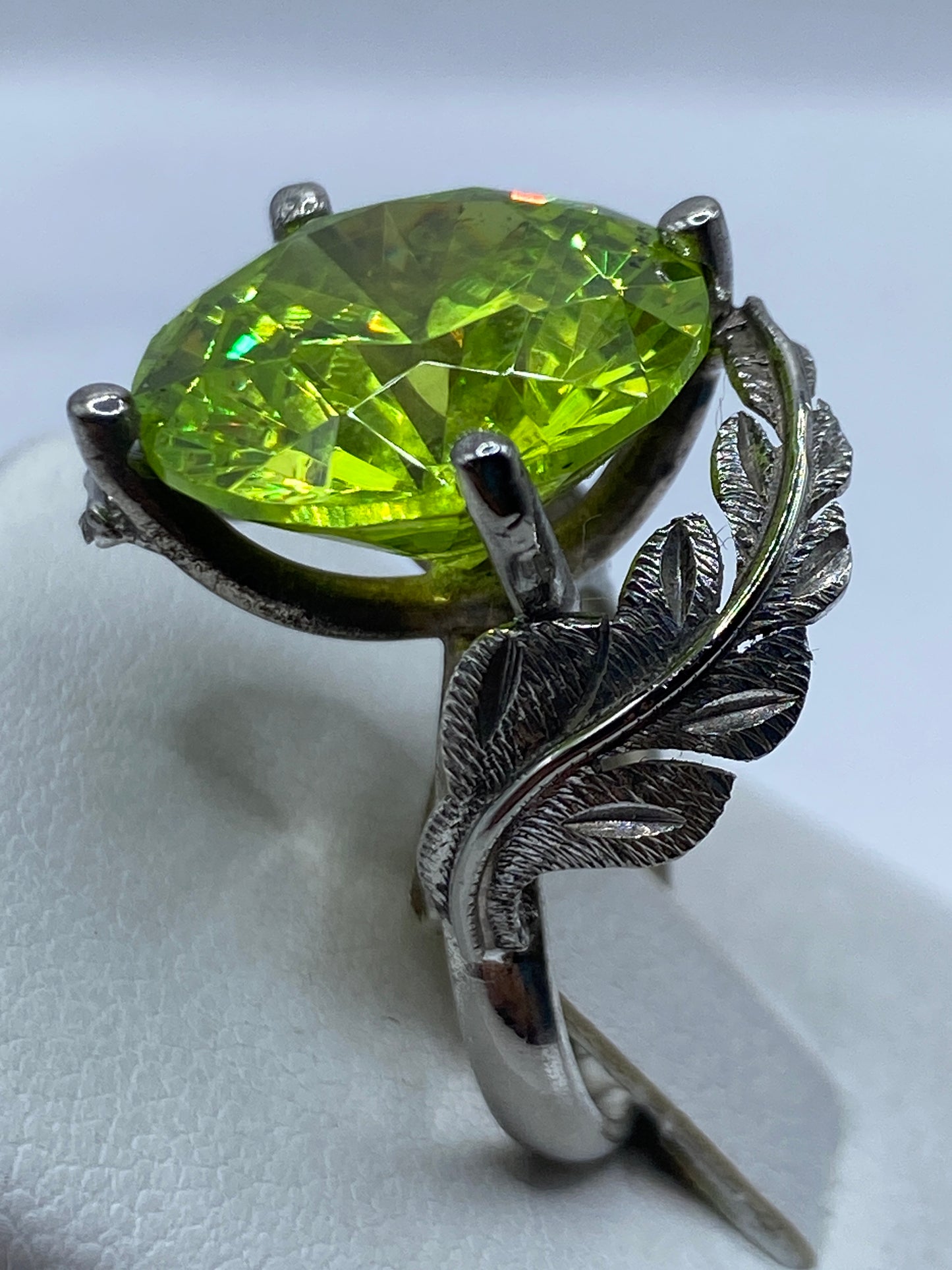 Anillo en dedo de mujer con circonia verde brillando bajo luz natural