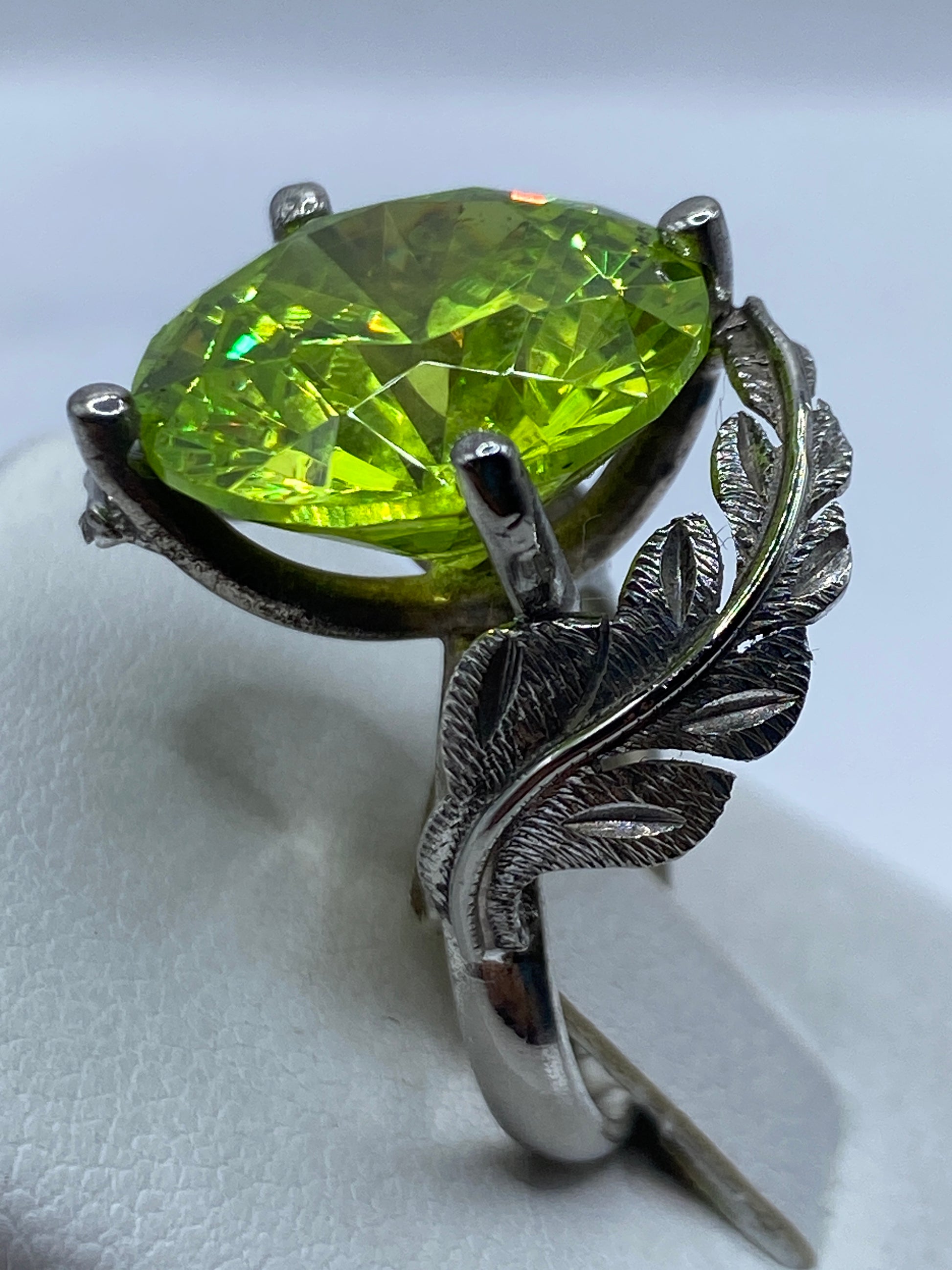 Anillo en dedo de mujer con circonia verde brillando bajo luz natural