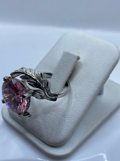 Vista frontal del anillo solitario rosa mostrando el tallado de alas de plata