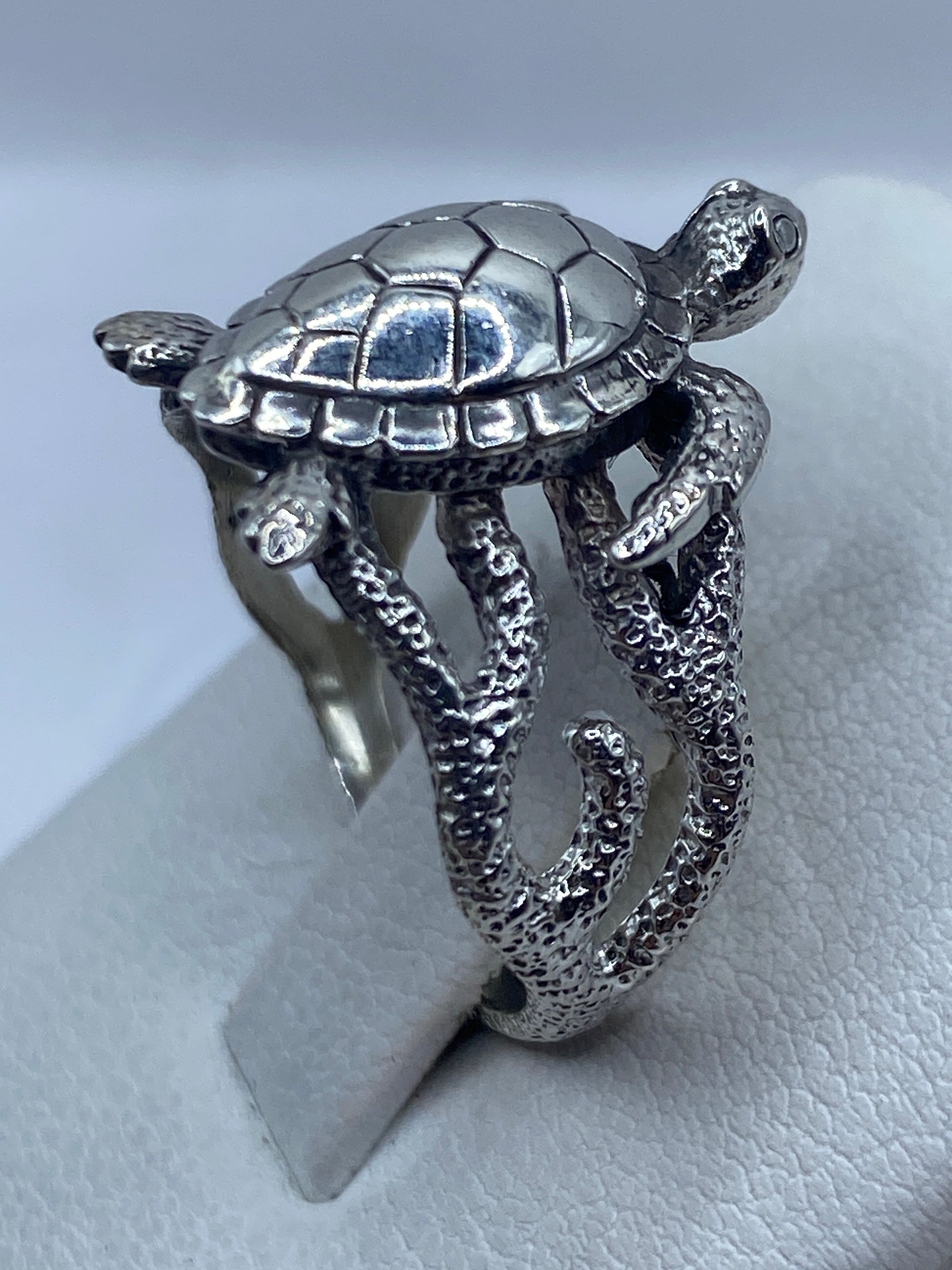 Anillo de plata .950 en la mano de una mujer, con relieve artesanal de tortuga