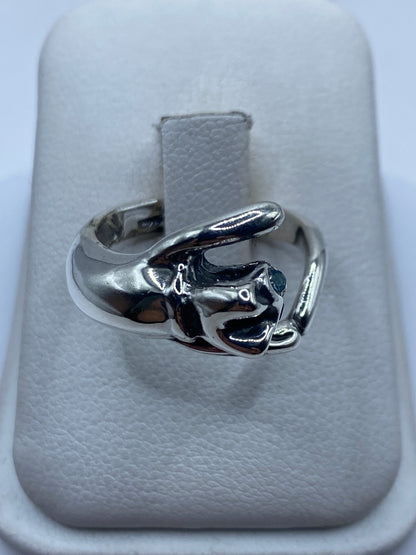 Anillo de plata con mano escultural engastando circonia azul, visto en la mano de una mujer