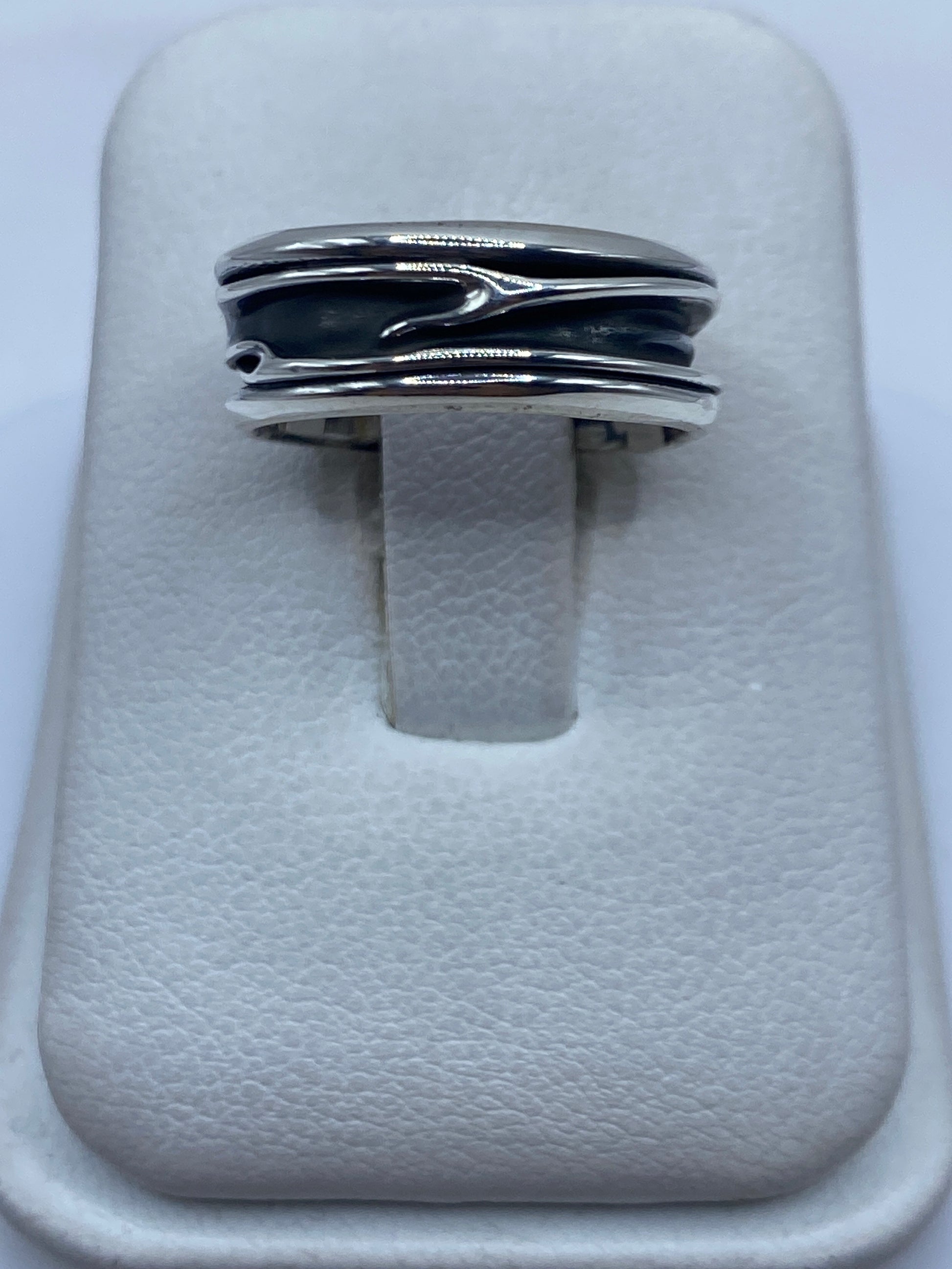 Anillo de plata con bandas superpuestas en los dedos de una persona