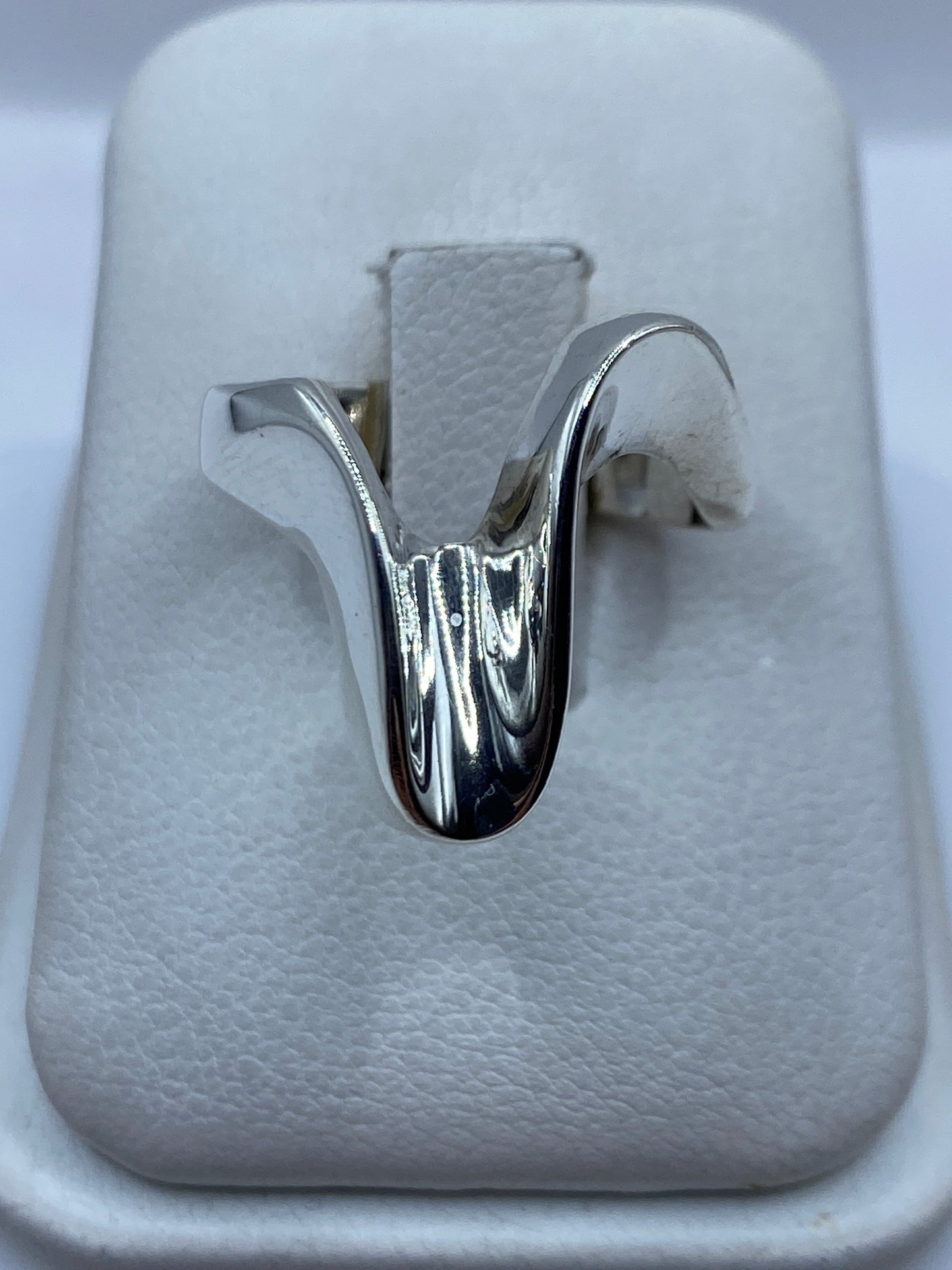 Anillo de plata fluido en forma orgánica, vista frontal sobre el dedo