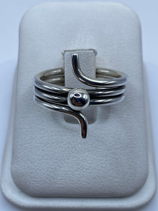 Anillo de plata giratorio con bandas pulidas, posado sobre estuche blanco