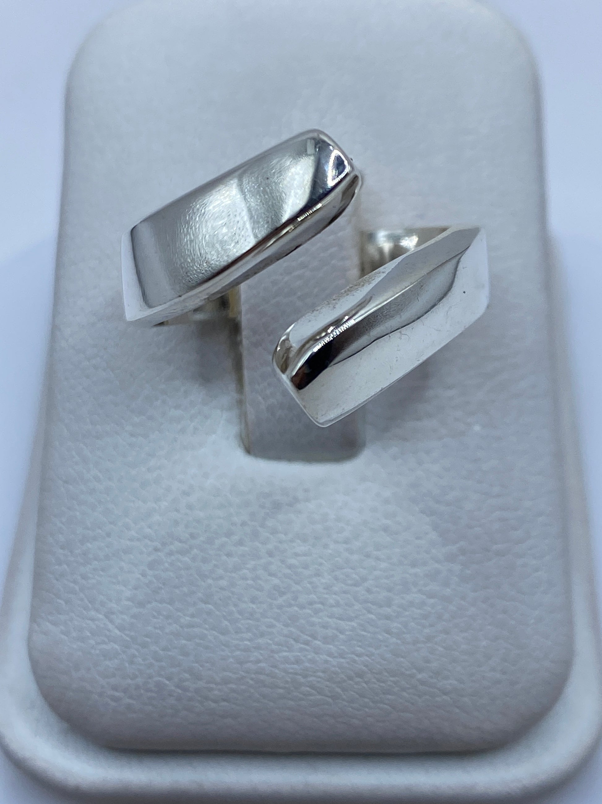 Anillo de plata geométrico ajustable sobre dedo, mostrando diseño moderno pulido