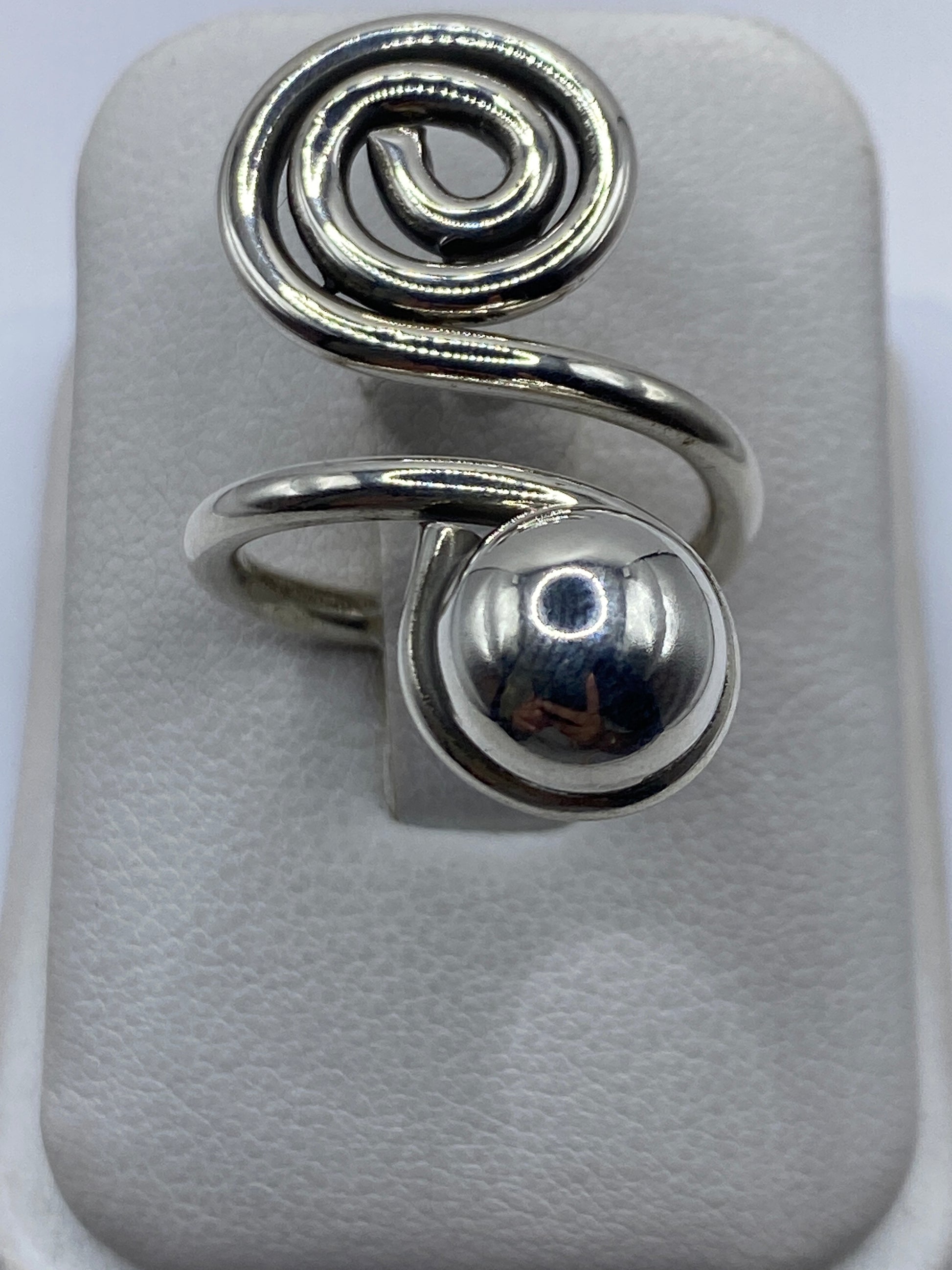 Anillo de plata calado ajustable con diseño en espiral en la mano de una mujer