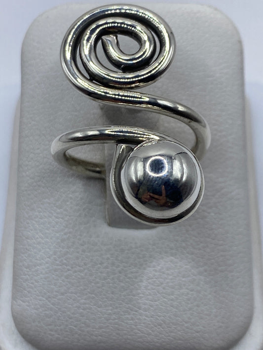 Anillo de plata calado ajustable con diseño en espiral en la mano de una mujer