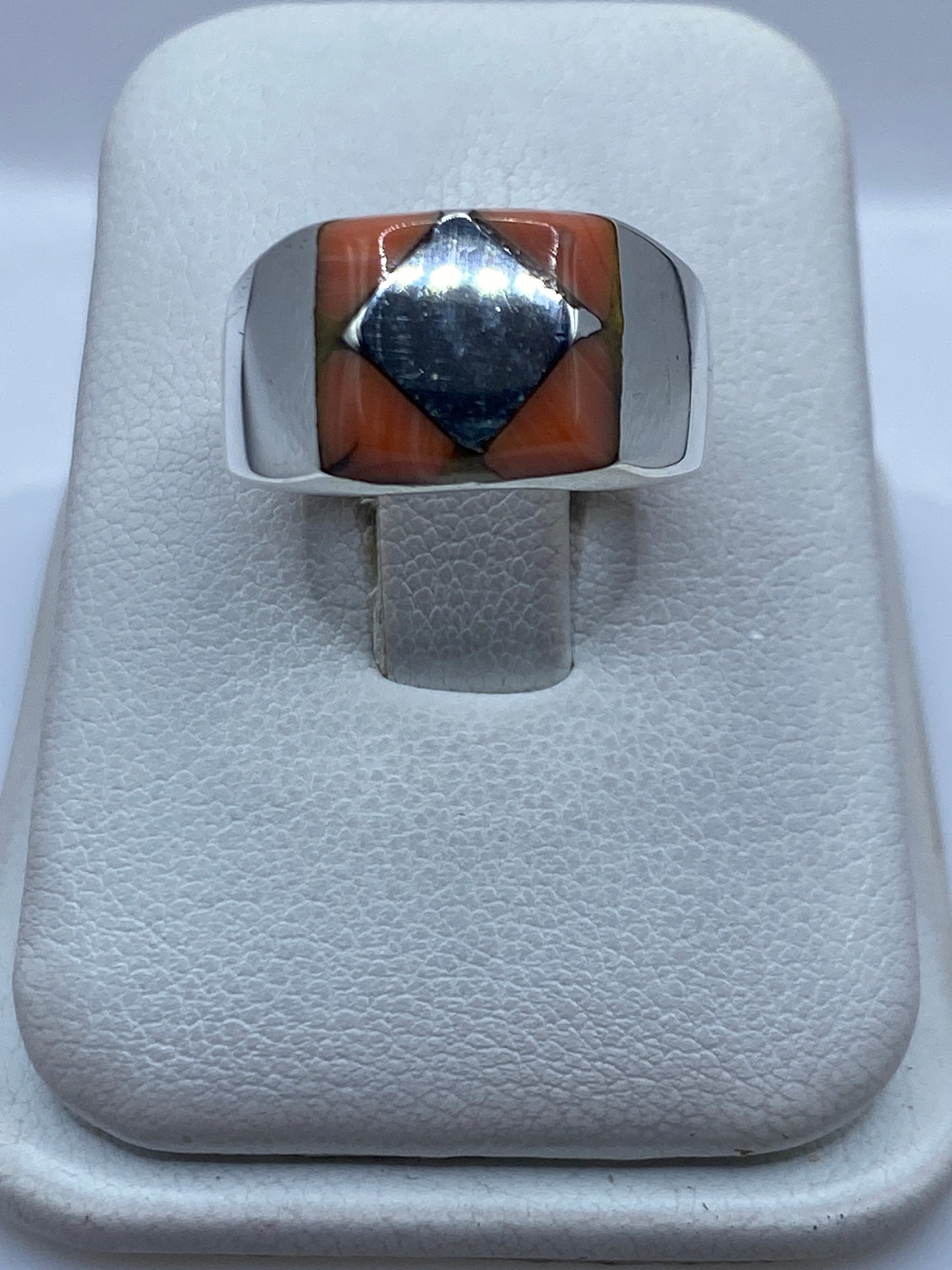 Anillo de plata .925 con piedra engastada a mano, vista frontal sobre joyero blanco
