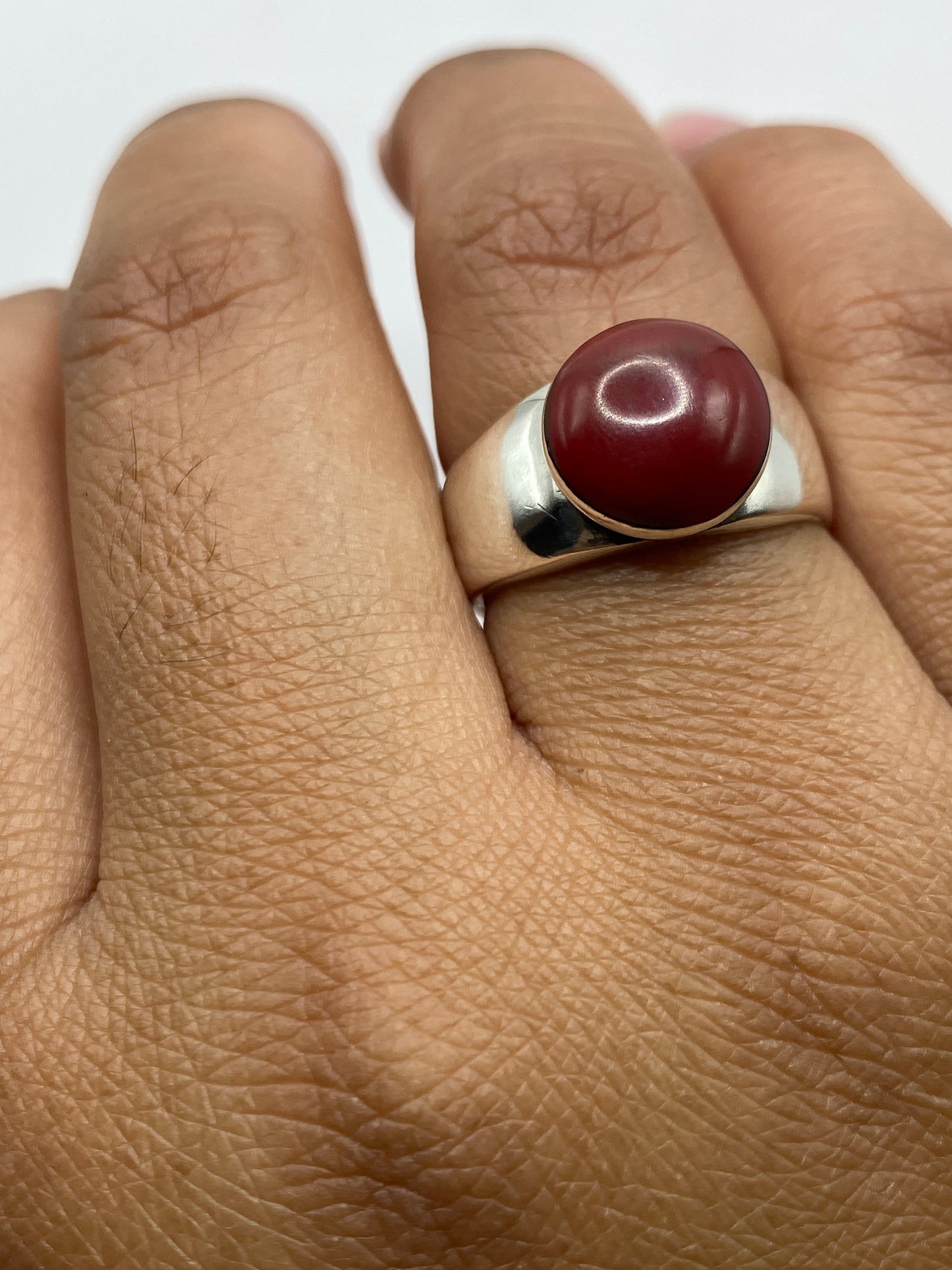 Anillo de plata con coral en el dedo, mostrando el look moderno y versátil