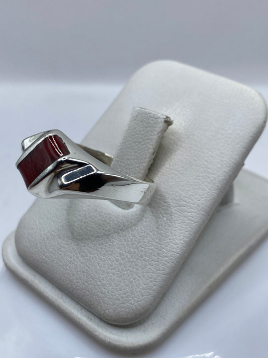 Anillo de plata coral rojo en mano, mostrando el brillo del pulido y la profundidad del engaste