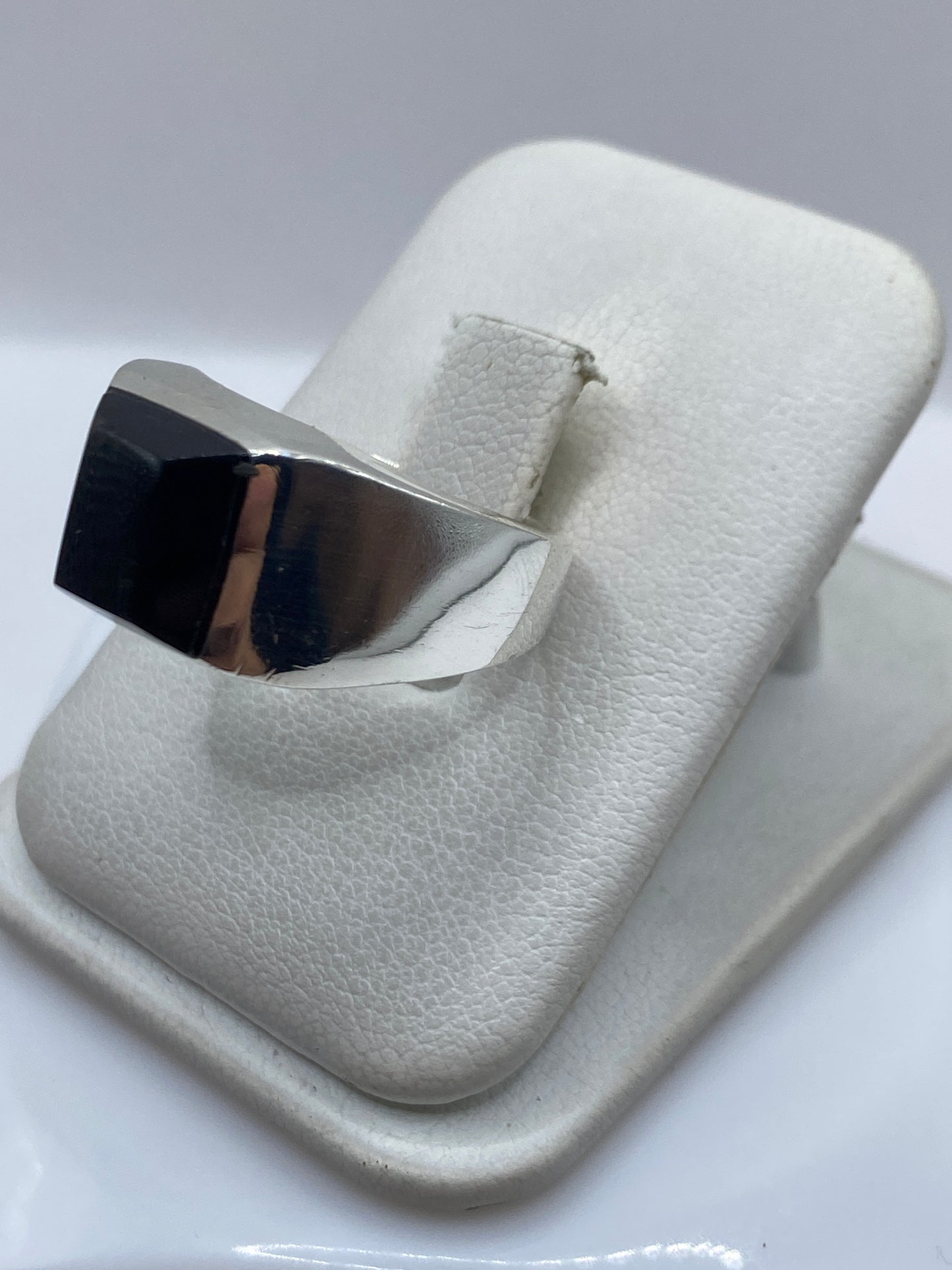 Anillo de plata con ónix negro en la mano, mostrando el engaste pulido