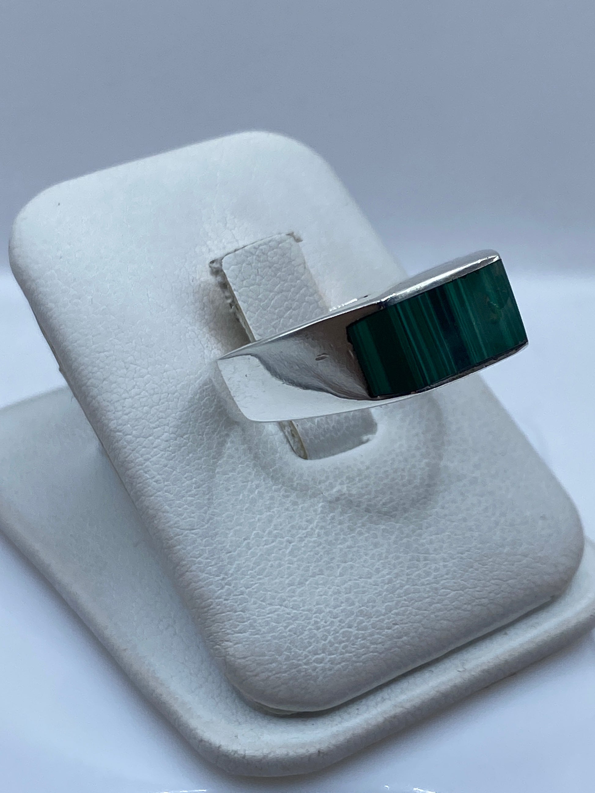 Anillo de plata malaquita verde en dedo de hombre, mostrando el peso y presencia