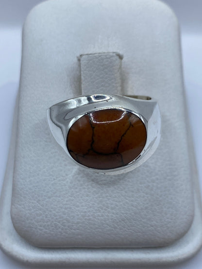 Anillo de plata .925 con piedra café engastada, visto de frente en estuche blanco