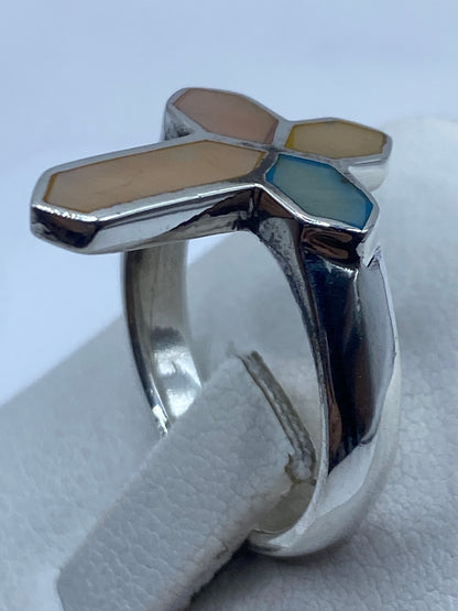 Anillo cruz en la mano de una persona, visto de frente, piedras brillantes