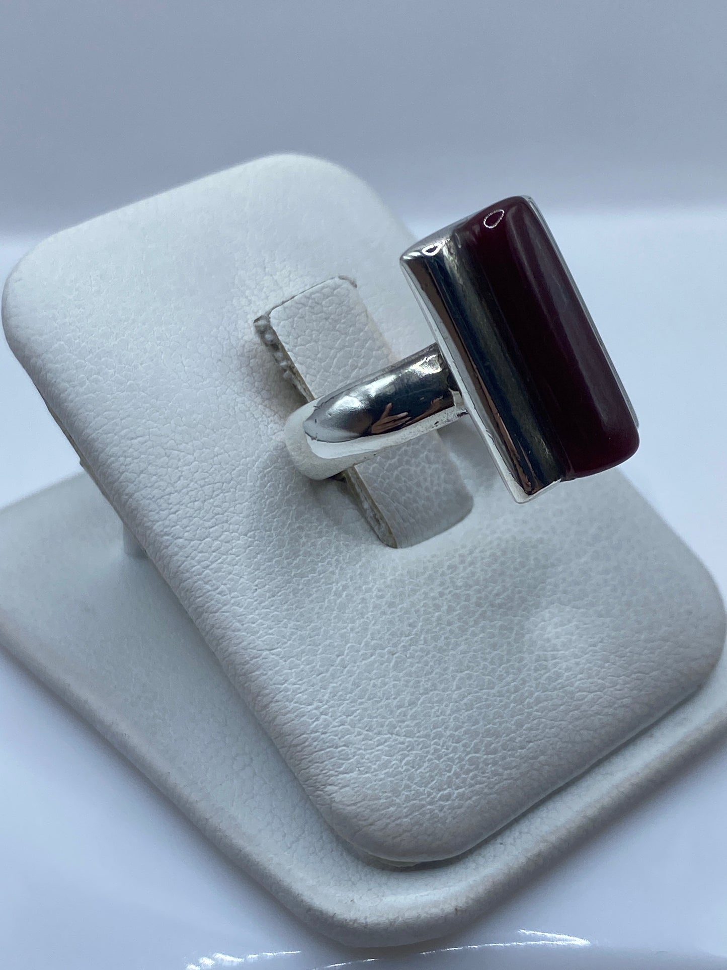 Detalle frontal del anillo de coral rojo engastado en marco de plata pulida