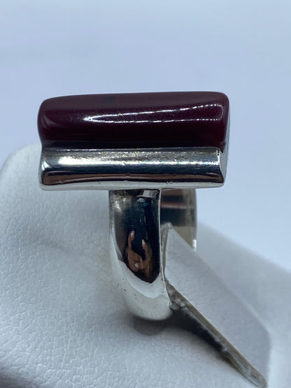 Anillo en mano mostrando el brillo del coral rojo y la plata pulida