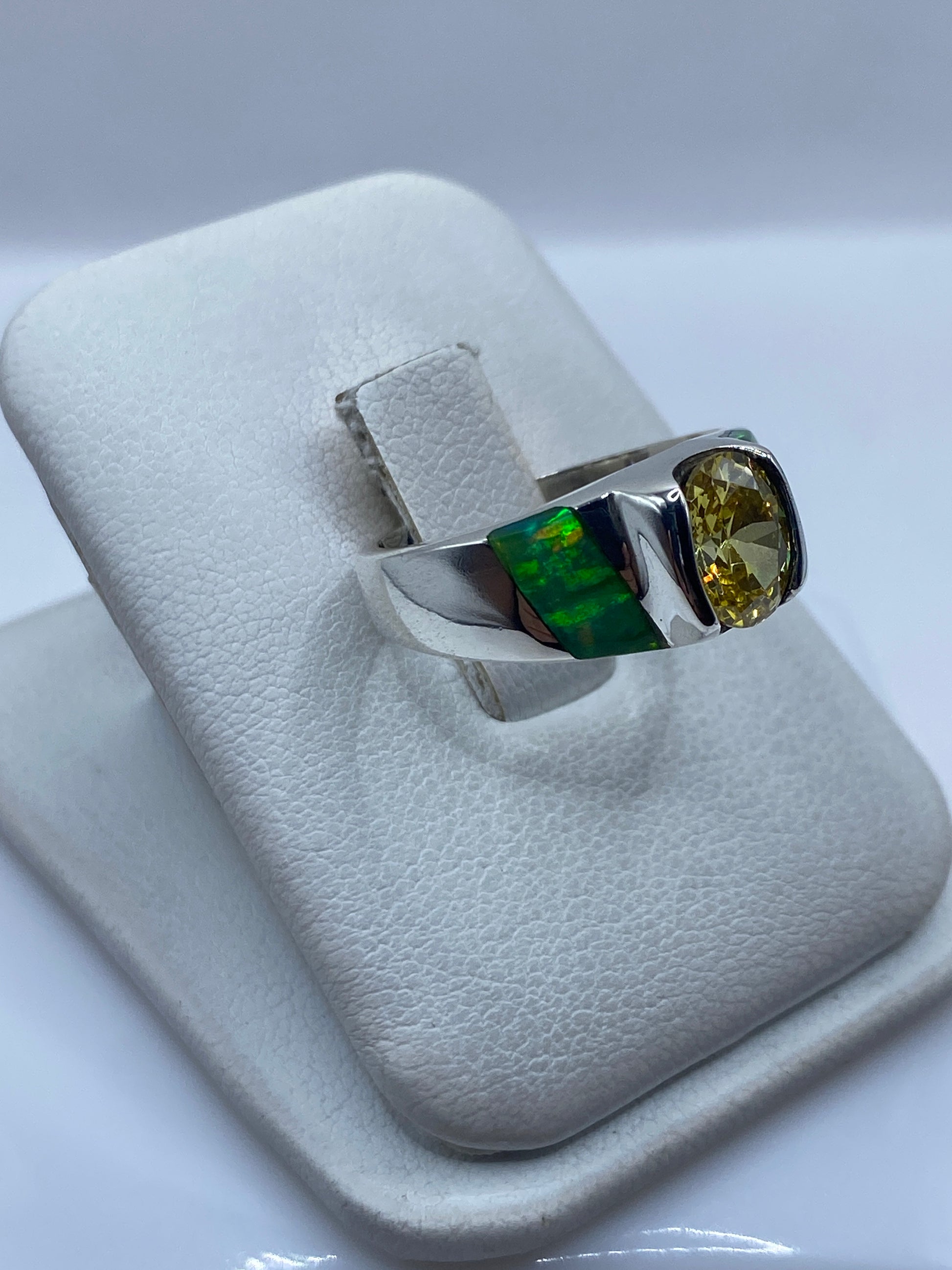 Vista lateral del anillo combinado con ópalo de fuego y perfiles verdes de incrustación