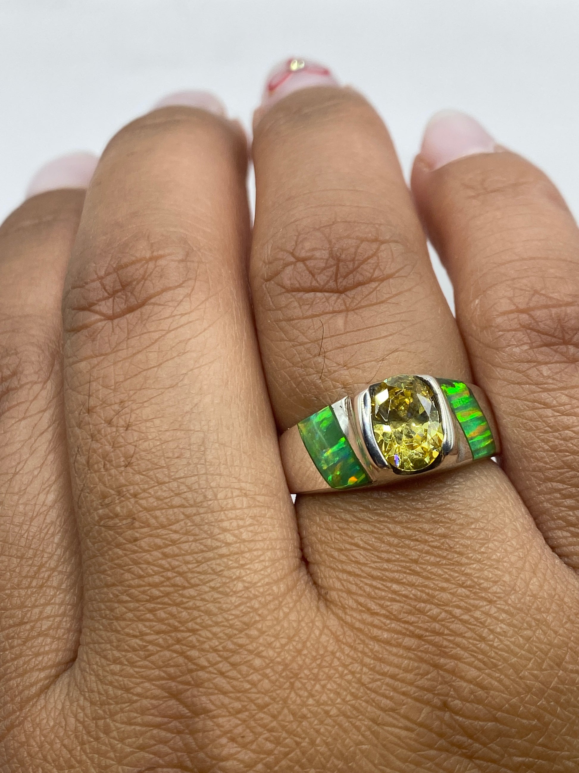 Anillo puesto en dedo, mostrando el brillo del ópalo de fuego verde limón en la caña de plata