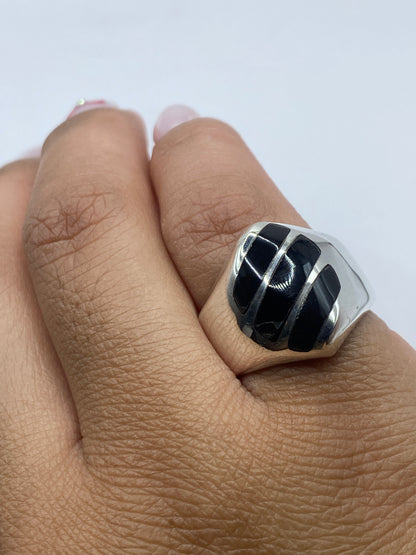Anillo sobre fondo blanco con ónix negro pulido y reflejos de plata